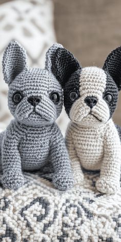 two small crocheted dogs sitting next to each other on top of a bed