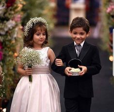 two young children dressed in formal wear walking down the aisle