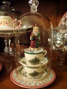 a glass cloche with a cup and saucer underneath it on top of a table