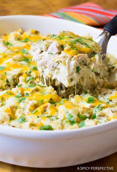 a spoon scooping some food out of a casserole dish with chicken and cheese