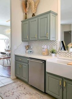 a kitchen with green cabinets and white counter tops, an area rug on the floor