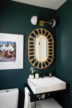 a white sink sitting under a mirror next to a toilet