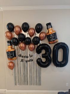 the 30th birthday balloons are hanging on the wall and there is a bottle of booze next to it