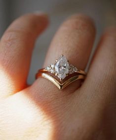 a woman's hand with a gold ring and two diamond rings on her fingers