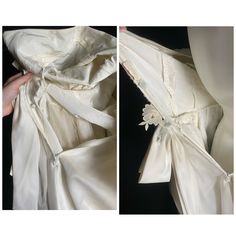 the back and side views of a wedding dress with white flowers on it, being held up by a woman's hand