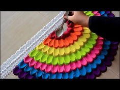 a person cutting paper with scissors on top of a colorful table cloth that is shaped like a fan