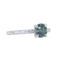 a green and white diamond ring with diamonds on the band, set in 18k white gold