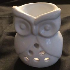 an owl shaped white vase sitting on top of a black cloth covered tablecloth, with its eyes wide open