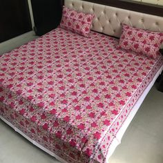 a bed with pink and white bedspread on top of it in a room