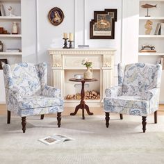 a living room with two chairs and a table in front of a fire place on the wall