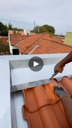 a man working on the roof of a house with an orange tiled roof and red tile roofs