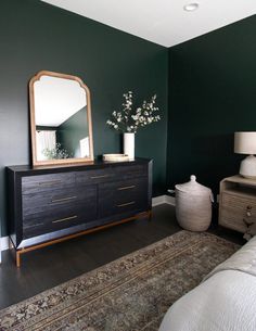 a bedroom with dark green walls and white furniture