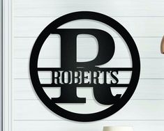 a metal sign that says robert's on the side of a white wall next to a lamp