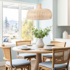 a dining table with four chairs and a vase on it in front of a window