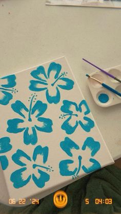 a painting with blue flowers on it next to paintbrushes and an easel