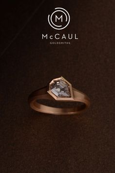 a diamond ring sitting on top of a brown table next to a black background with the words mccaul