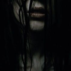 a woman's face with long hair in the dark