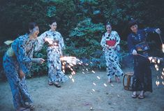 four women in kimonos are playing with sparklers