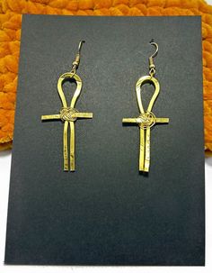 Absolutely stunning Ankh Earrings, meticulously handcrafted from non-tarnishing aluminum wire for timeless beauty. These exquisite drop earrings feature an intricate 3 inch design, elegantly woven with golden wire. Embrace the symbol of life and immortality with these unique, eye-catching earrings that are as meaningful as they are beautiful.  These Ankh earrings are not just accessories; they are a statement of your unique style and the enduring essence of life. Perfect for both daily wear and special occasions, they make a thoughtful gift or a delightful addition to your own jewelry collection. Length of earrings ( About 3 inches)   From ear hook to end Ankh Earrings, Black Owned Business, Symbol Of Life, African Earrings, Life Symbol, Earrings Statement, Ear Hook, Cute Earrings, Earrings Gold