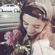 a young woman holding flowers in her hand while sitting in the back seat of a car