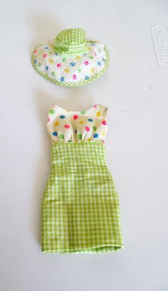 the doll is wearing a green and white dress with polka dots on it, hat