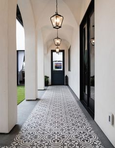 a long hallway with black and white tiles on the floor, along with two lamps