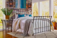 a bedroom with a metal bed frame and blue pillows on top of the bed, along with two side tables