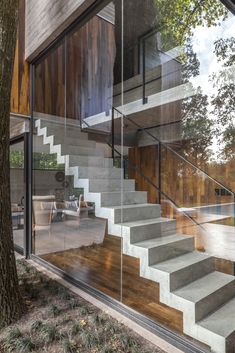 the stairs lead up to the upper level of this modern home, which has glass walls and wood flooring