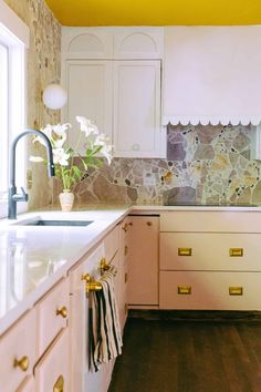 a kitchen with white cabinets and gold pulls on the drawers, marble backsplash