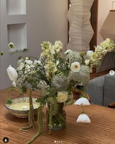 a vase filled with white flowers sitting on top of a wooden table next to a plate