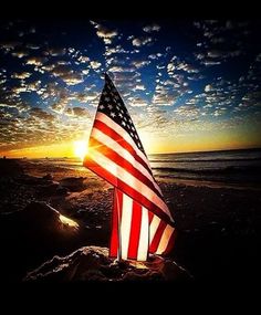 an american flag on the beach at sunset