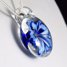 This unusual and unique pendant has a realistic blue and white glass 3D flower inside a solid glass - this isn't resin or a real flower, it's all made entirely of glass! I've used a cobalt blue over white, which I've graduated in tone and to form bands on the petals to make the flower look more realistic, also giving the edges and centre a darker rim of blue. In the centre I've added some yellow 'stamens' to make it look more realistic, where some bubbles have clustered around them to add a dew Blue Flower Necklace, Red Flower Necklace, Women Flower, Flower Jewelry, Unique Pendant, Blue Flower, Flower Pendant, Real Flowers, Flower Making