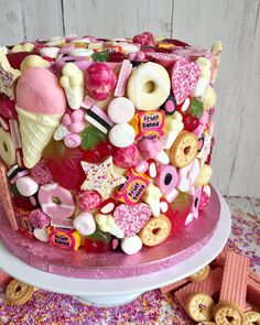 a pink cake covered in lots of different candies and donuts on top of it