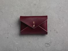 a small red envelope sitting on top of a cement floor next to a white wall