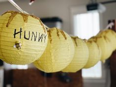 yellow paper lanterns with writing on them hanging from hooks