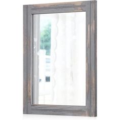 a wooden framed mirror sitting on top of a white table next to a curtained window