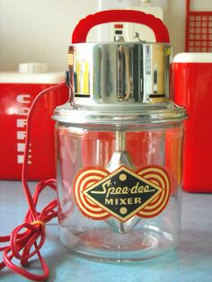 a glass jar with a red handle sitting on top of a table