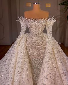 a white wedding dress on display in front of a mannequin headdress