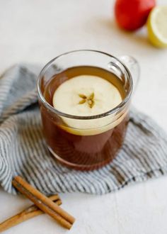 an apple cider is sitting on a towel next to two cinnamon sticks and apples