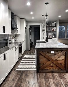 a kitchen with an island made out of wooden planks and white cabinets, along with stainless steel appliances