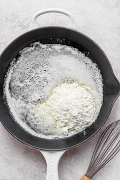 an iron skillet with flour in it next to a whisk