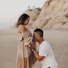 a man kneeling down next to a woman on the beach