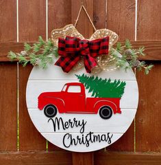 a christmas ornament hanging on a wooden fence with a red truck and pine tree