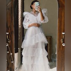 a woman in a white dress taking a selfie with her cell phone while standing in front of a mirror