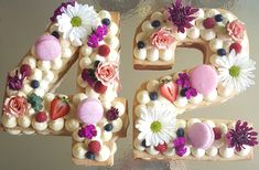 the number twenty four decorated with flowers and fruit is shown in front of a frosted cake