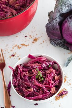 a white bowl filled with red cabbage next to a metal fork