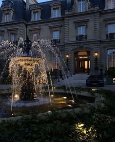 a fountain in front of a large building at night