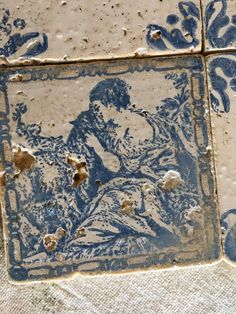 an old tile with blue and white designs on the outside, depicting a man sitting in a chair