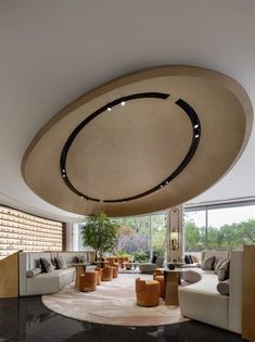 a living room filled with lots of furniture next to a large round ceiling light fixture