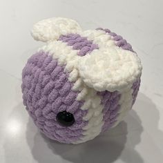 a purple and white stuffed animal with black eyes